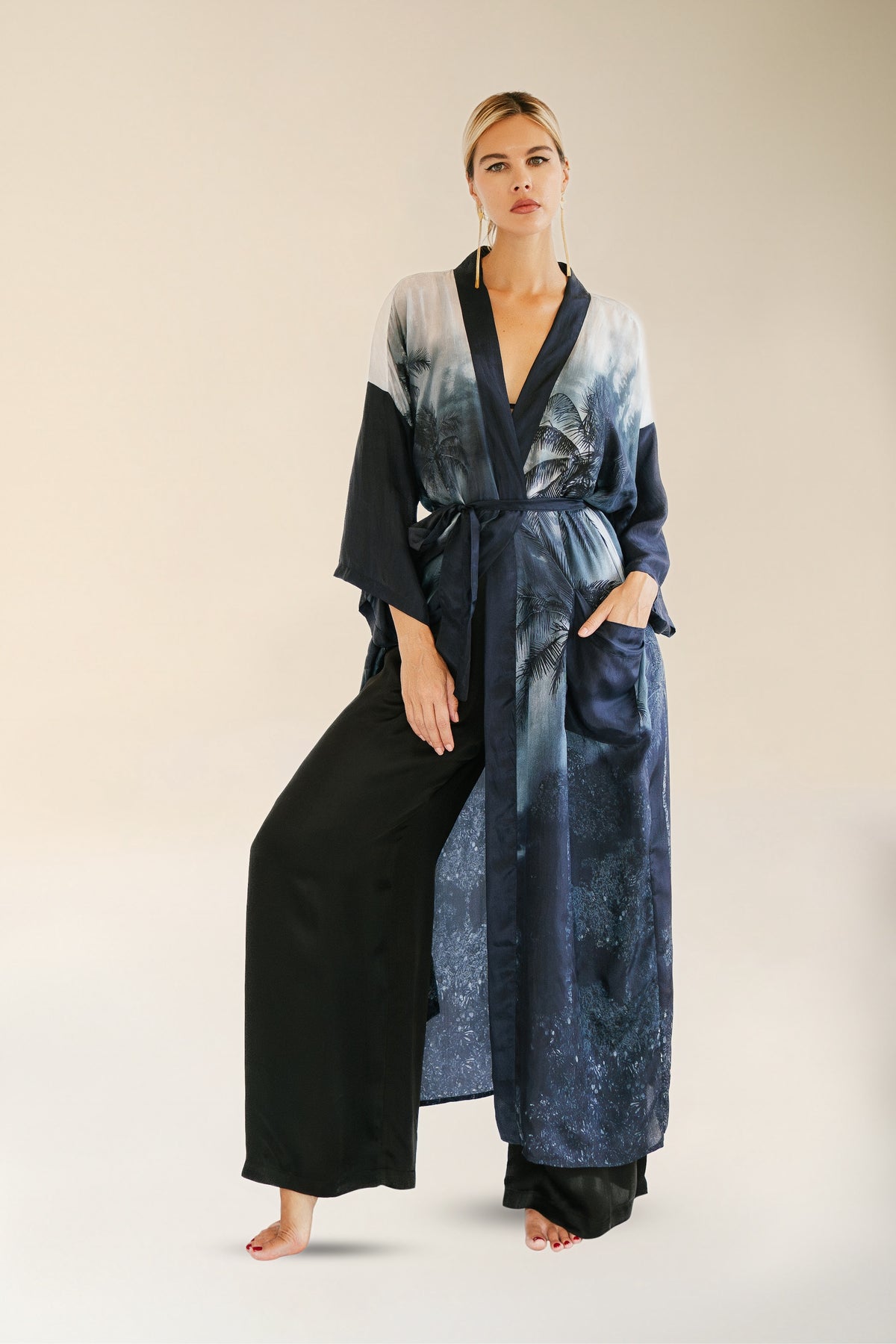 Woman wearing a long, dark blue and black robe with a gradient effect on a beige background